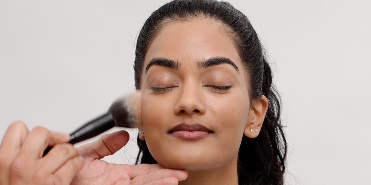 Makeup artist applying bronzer to complement a brown smokey eye